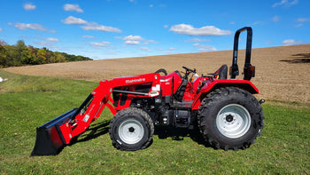 Red Mahindra tractor with loader, sturdy design, ideal for farming and landscaping, featuring robust tires.