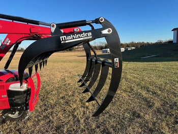 Mahindra loader rake attachment in black for heavy-duty material handling on tractor.